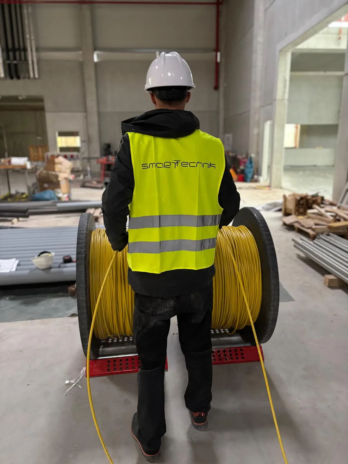 smaRTtechnik technician pulling fiber from a cable drum in an industrial hall